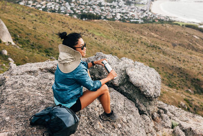 Side view of woman sitting on rock