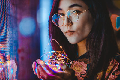 Portrait of young woman holding sunglasses outdoors