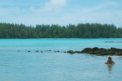 Rear view of person swimming in sea against sky