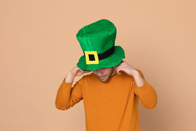 Man wearing green hat standing against beige background