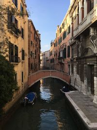 Bridge over canal amidst buildings against sky in city