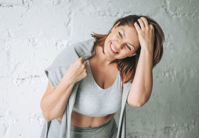 Portrait of a smiling young woman standing against wall