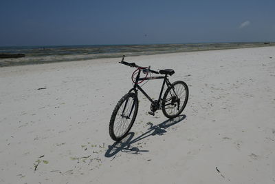 Bicycle on beach against clear sky