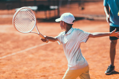 Boy playing tennis in court