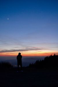 Silhouette man standing against orange sky