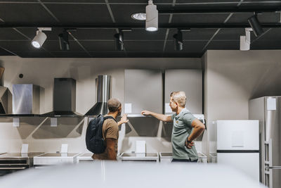 Salesman advising male customer in buying appliance at electronics store