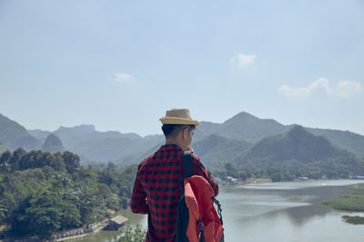 Rear view of man standing by mountain against sky