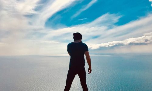 Rear view of man looking at sea against sky