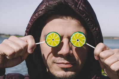 Close-up of man with eyes covered by lemon shape lollipops