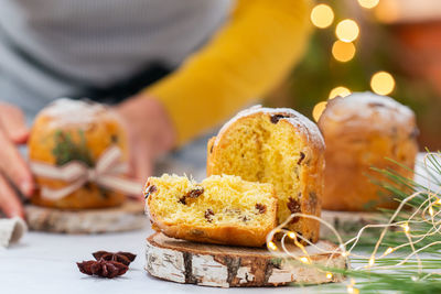 Traditional italian christmas cake panettone with festive decorations. female hands are holding cake