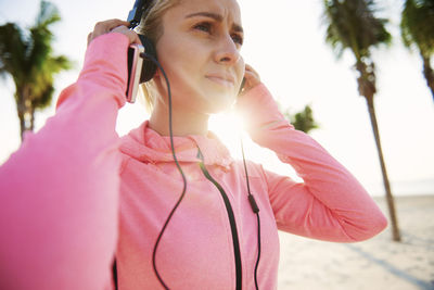 Portrait of young woman using mobile phone against sky