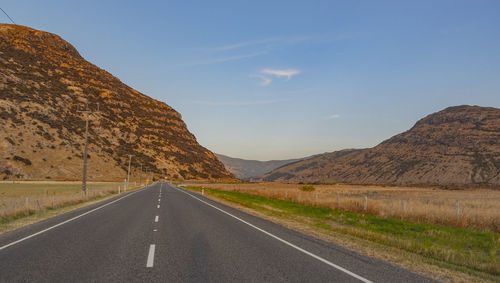 Road leading towards mountains against sky