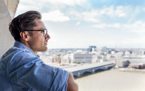 Uk, london, man looking at the city on a roof terrace