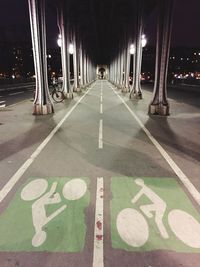 Bicycle lane sign below bridge in city at night