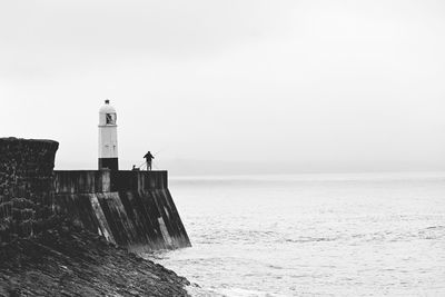 Lighthouse by sea against sky