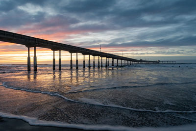 Pier over sea against sky during sunset