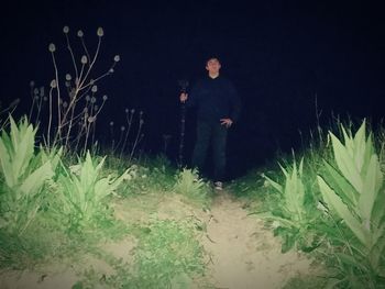 Man standing amidst plants at night