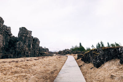 Footpath amidst rocks against clear sky