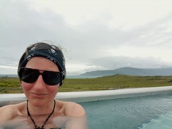 Portrait of young woman in swimming pool against sky