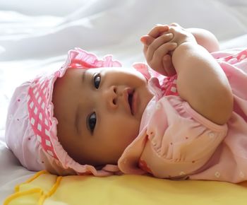 Close-up of cute baby lying on bed