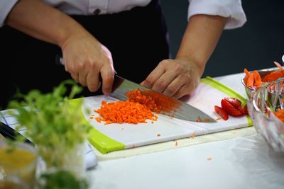 Midsection of person preparing food on cutting board