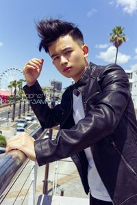 Side view of young man looking away against sky