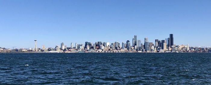 Sea by modern buildings against clear sky