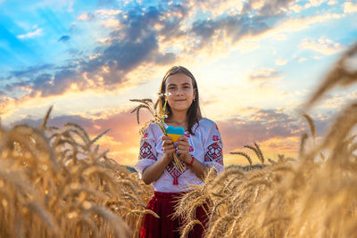 Portrait of young woman standing against sky during sunset