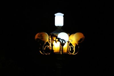 Close-up of illuminated light bulb against black background