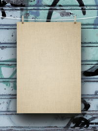Blank beige paper hanging from string against metallic shutter