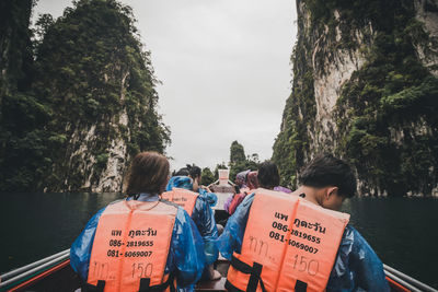 Rear view of people on boat against trees