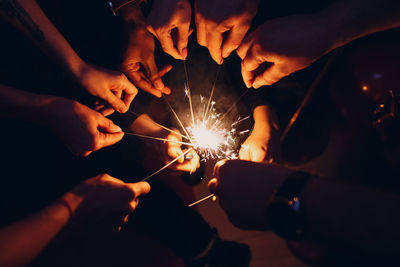 Low angle view of hands holding sparklers at night