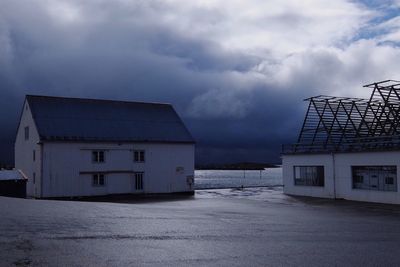 Houses at beach against cloudy sky