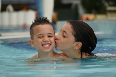 Portrait of father and son swimming in pool