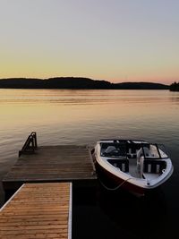 Boat moored in lake against sky during sunset