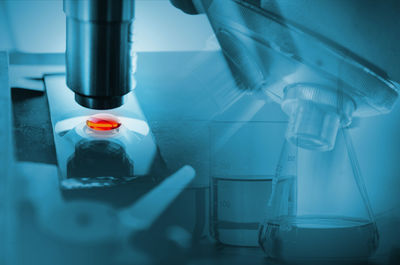 Digital composite image of scientist analyzing liquid using microscope