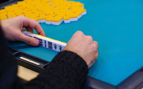 A mahjong table with an active game and the hands of a participant in the game.