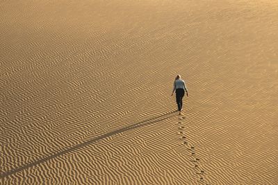 High angle view of woman walking on sand at desert