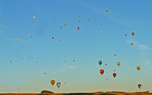 Hot air balloons flying over landscape against sky