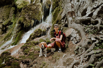 Full length of girl sitting on rock with her beagle dog