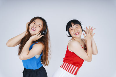 Lesbian couple listening music against gray background