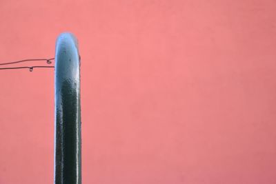 Close-up of metallic railing against coral background