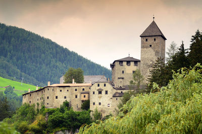 Castle by buildings against sky