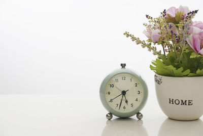 Close-up of flower vase on table against white wall