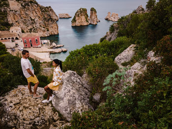 People standing on rock by sea