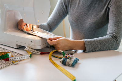 Midsection of teenage girl sewing textile at home