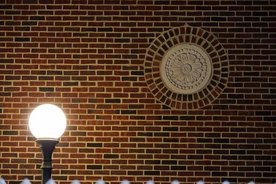Illuminated light bulb against brick wall