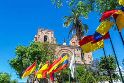 Low angle view of flags fluttering against cuenca cathedral