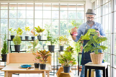 Young man looking at potted plant on table