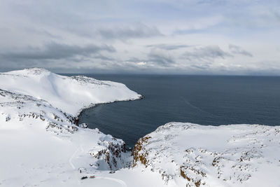 Scenic view of sea and snowcapped mountains against sky